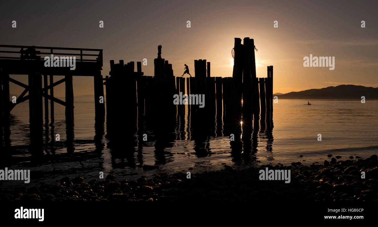 Wooden post on shore against sky during sunset Stock Photo