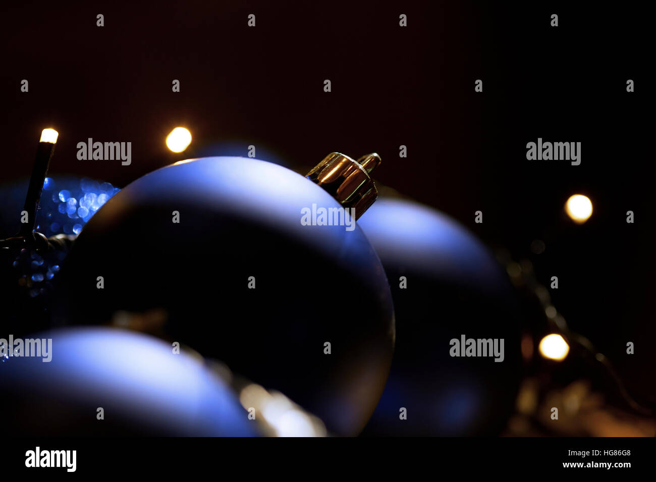 Close-up of christmas baubles with fairy lights in dark room Stock Photo