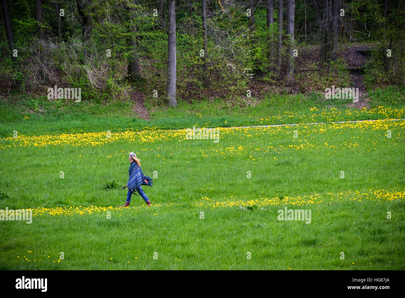 Hippie woman dressed in blue, walking on a green field Stock Photo
