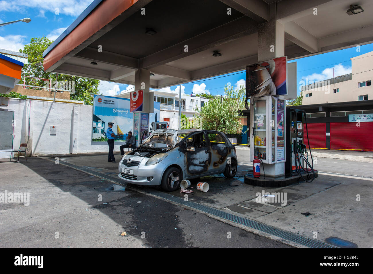A gas station in Mahebourg town, Mauritius Island. A burnt car next to