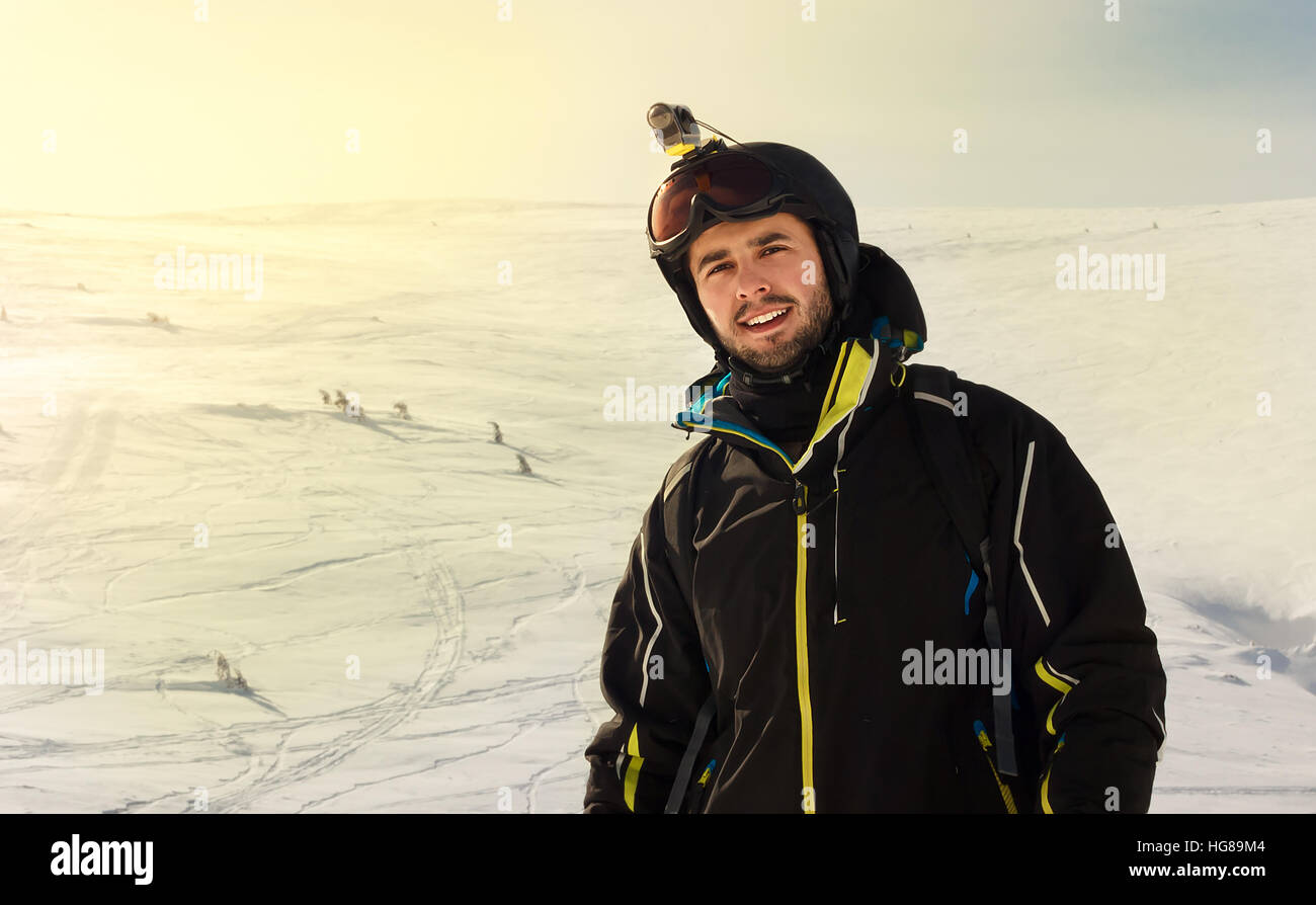 A young man with extreme camera on helmet on a snowy mountain Stock Photo