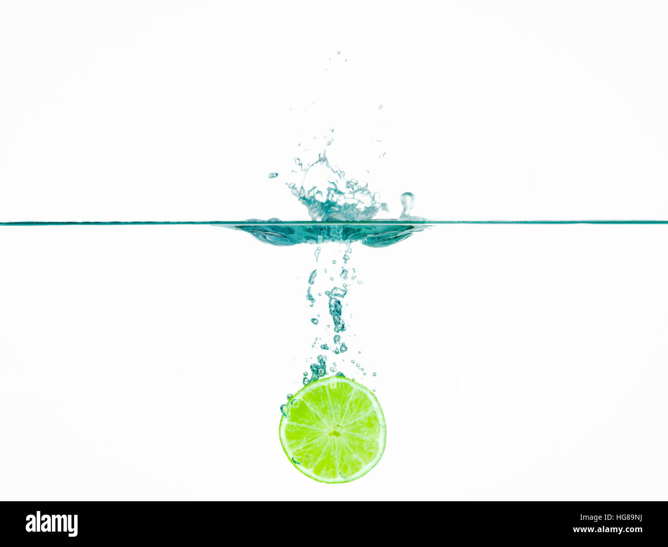 Lime slice in water against white background Stock Photo
