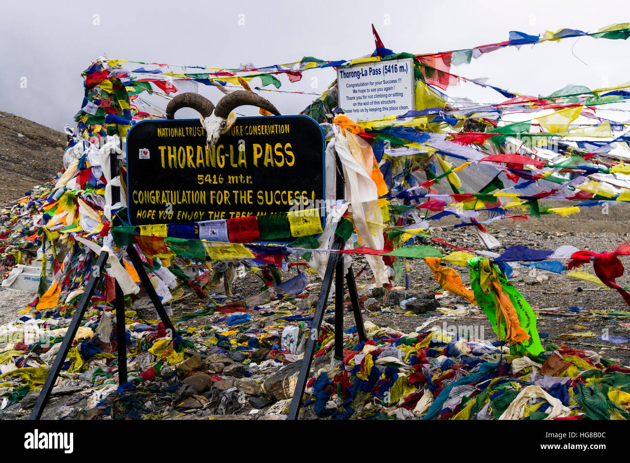 Tibetan prayer flags at sign Thorong-La Pass, 5416 m, pass between the Upper Marsyangdi and the Kali Gandaki valley Stock Photo
