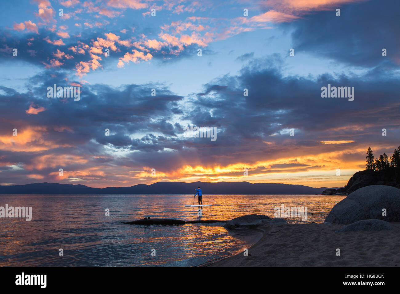 Man paddleboarding in lake against cloudy sky Stock Photo