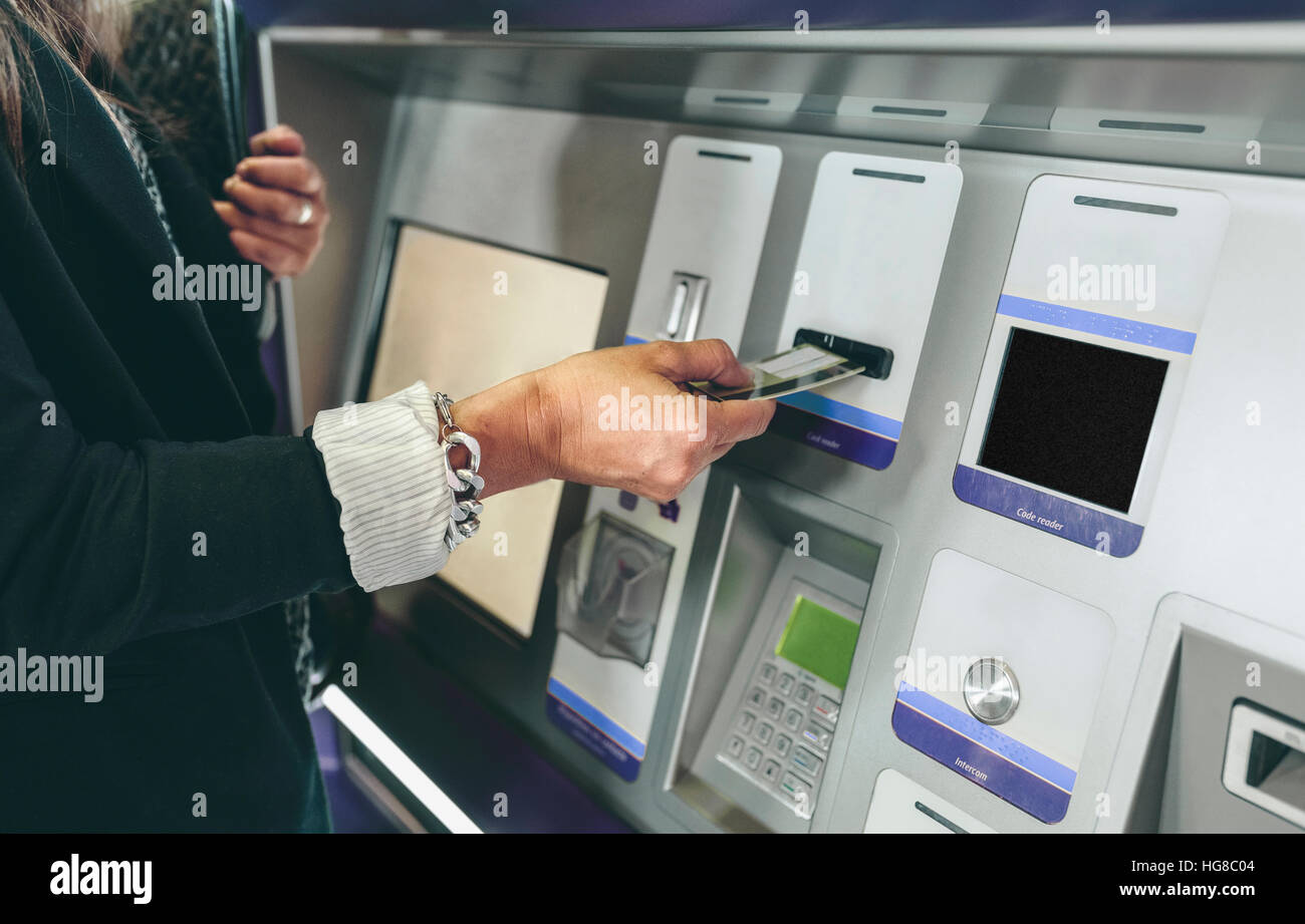 Midsection of woman inserting card in ATM machine Stock Photo