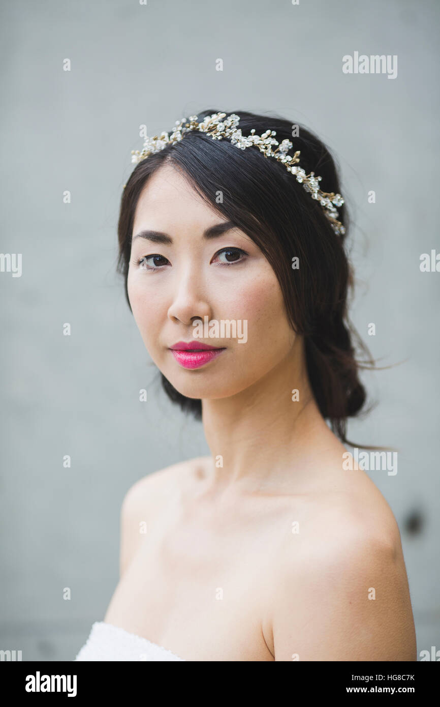 Portrait of woman wearing tiara while standing against white wall Stock Photo