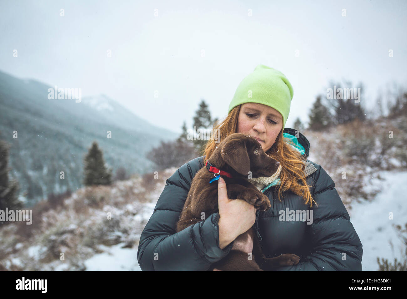 Woman with Chocolate Labrador standing against sky during winter Stock Photo