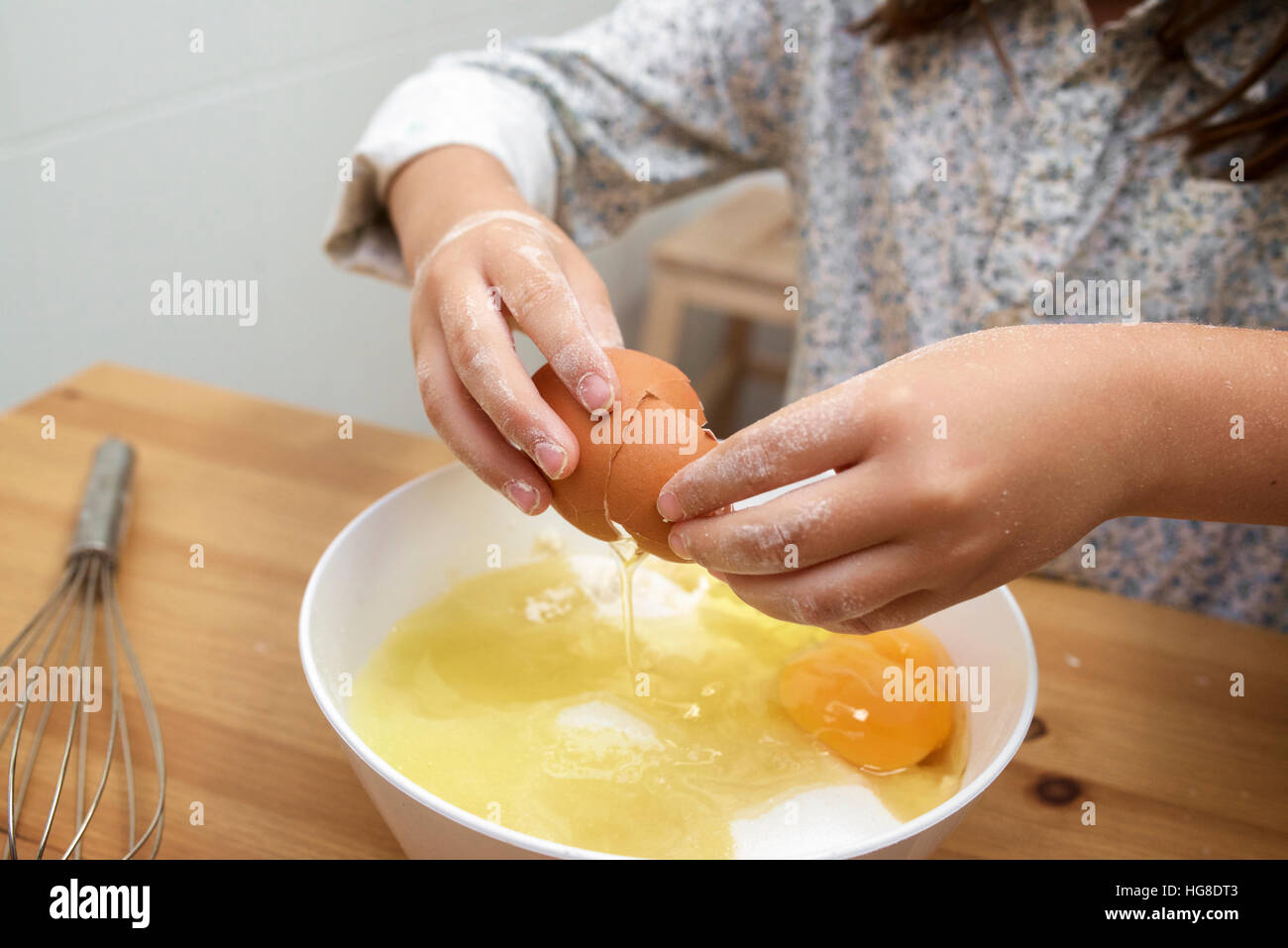 Cropped image of girl breaking eggs in bowl at table Stock Photo Alamy