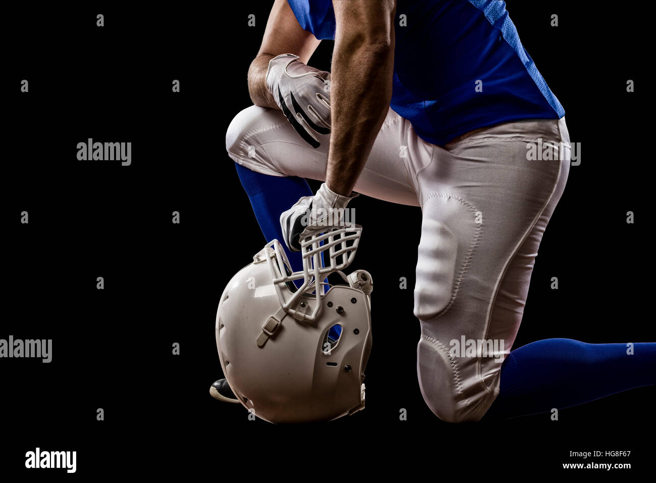 Football Player with a blue uniform on his knees, on a black background
