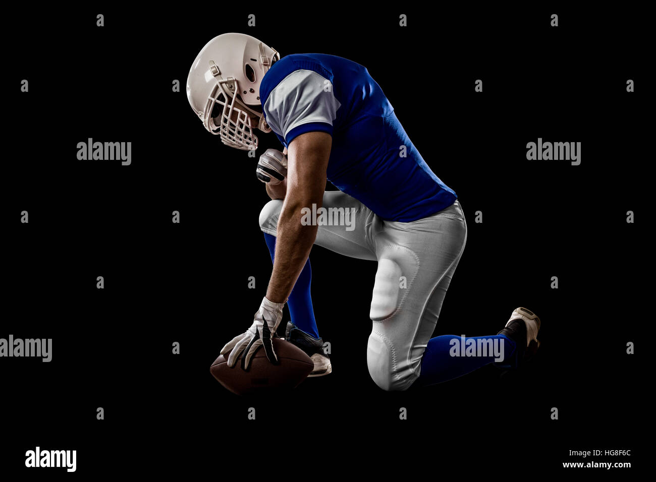 Football Player with a blue uniform on his knees, on a black background