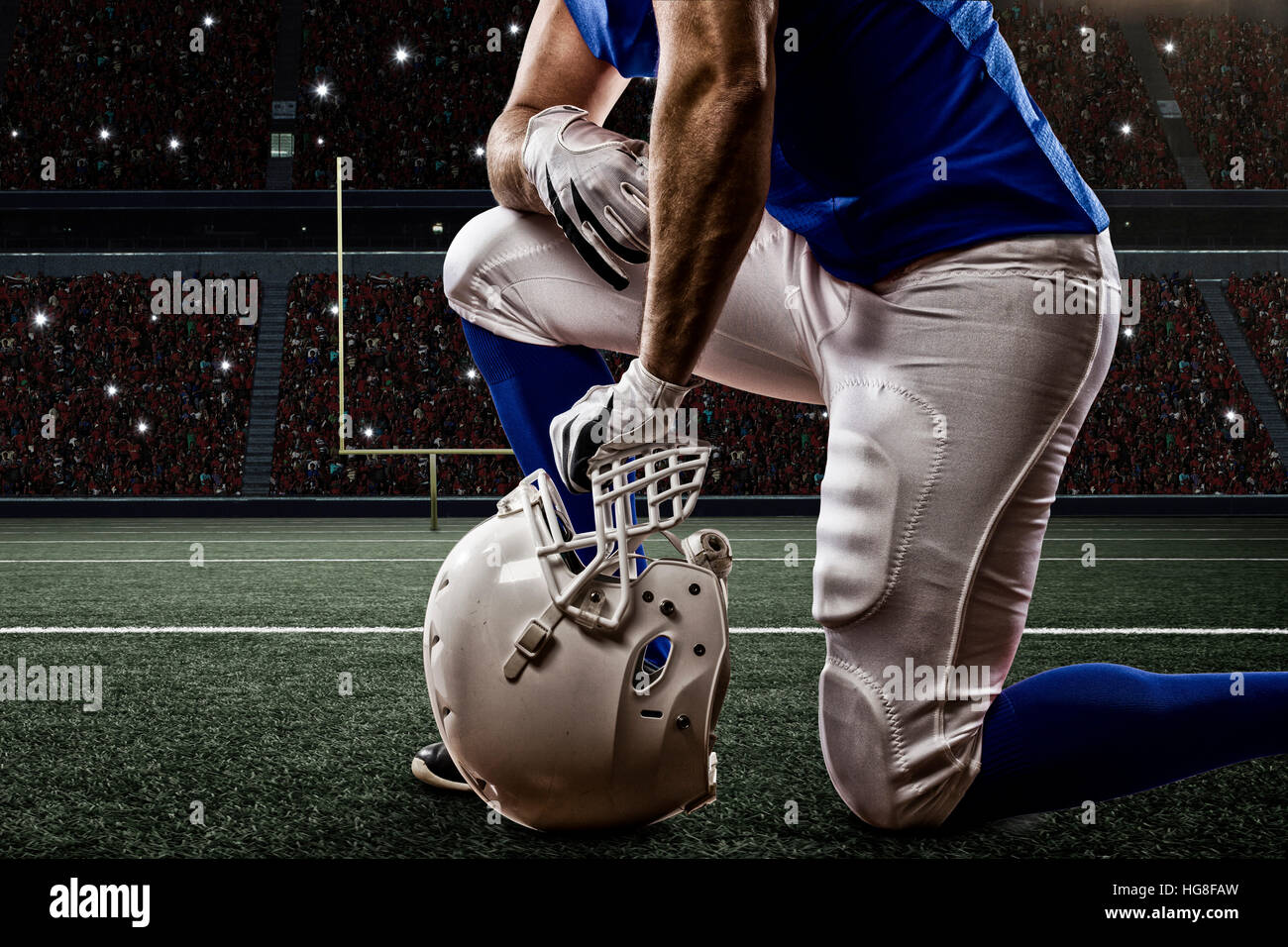 football-player-with-a-blue-uniform-on-his-knees-on-a-stadium-stock