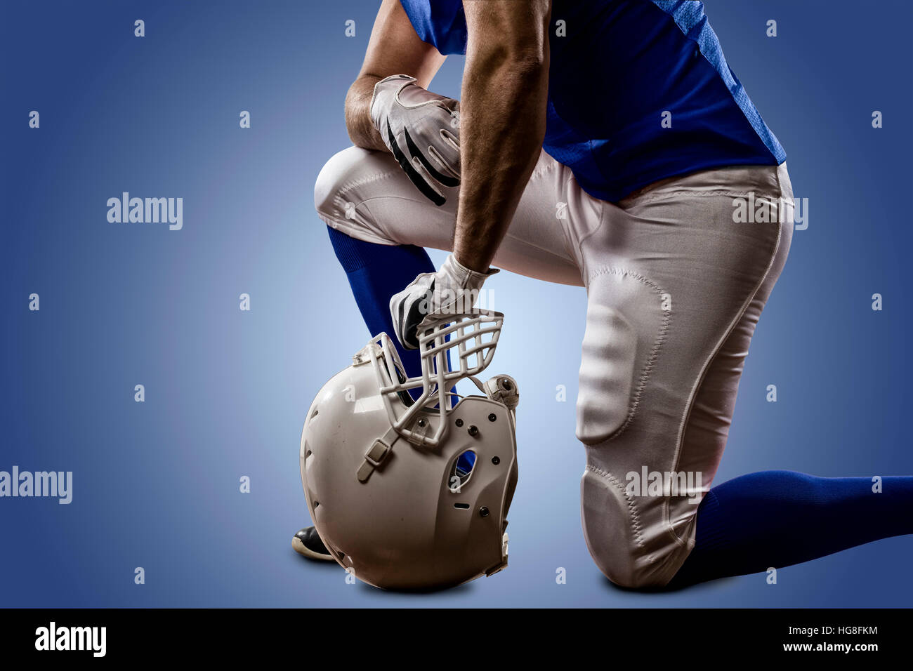 Football Player with a blue uniform on his knees, on a blue background