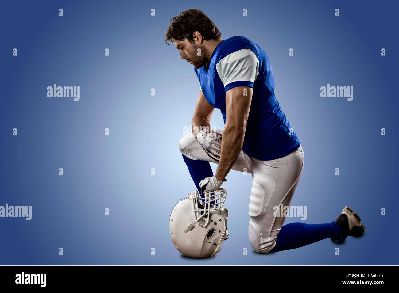Football Player with a blue uniform on his knees, on a blue background