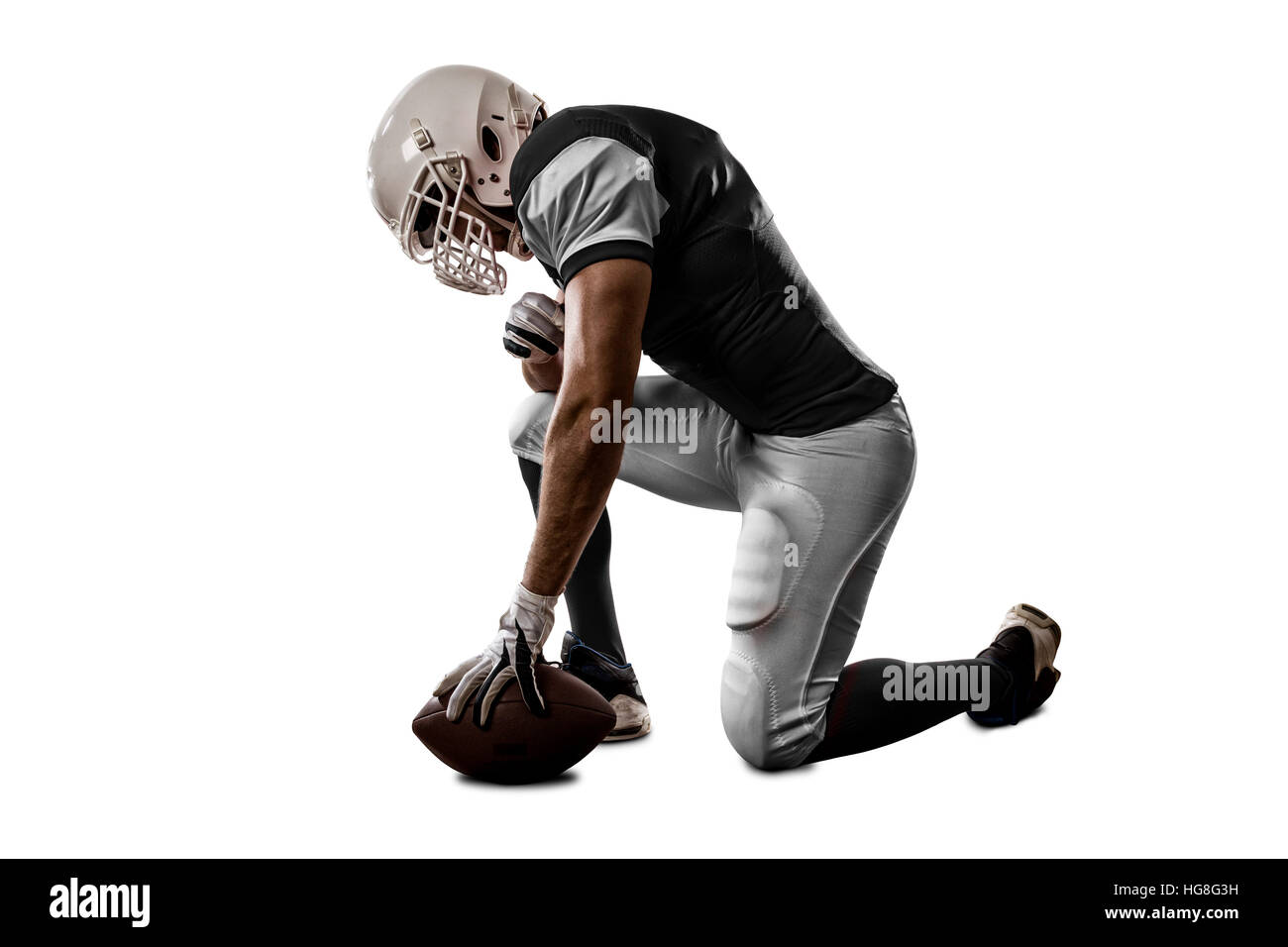 Football Player with a black uniform on his knees, on a white