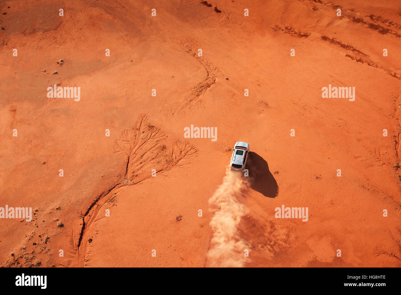 Bird's eye view looking over a car driving through the Australian outback red desert Stock Photo