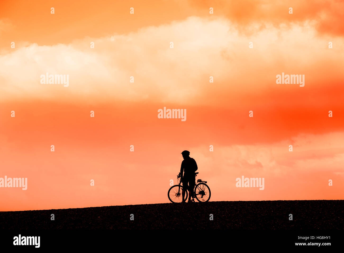 Mountain biker on Cley beach in the setting sun Norfolk Stock Photo