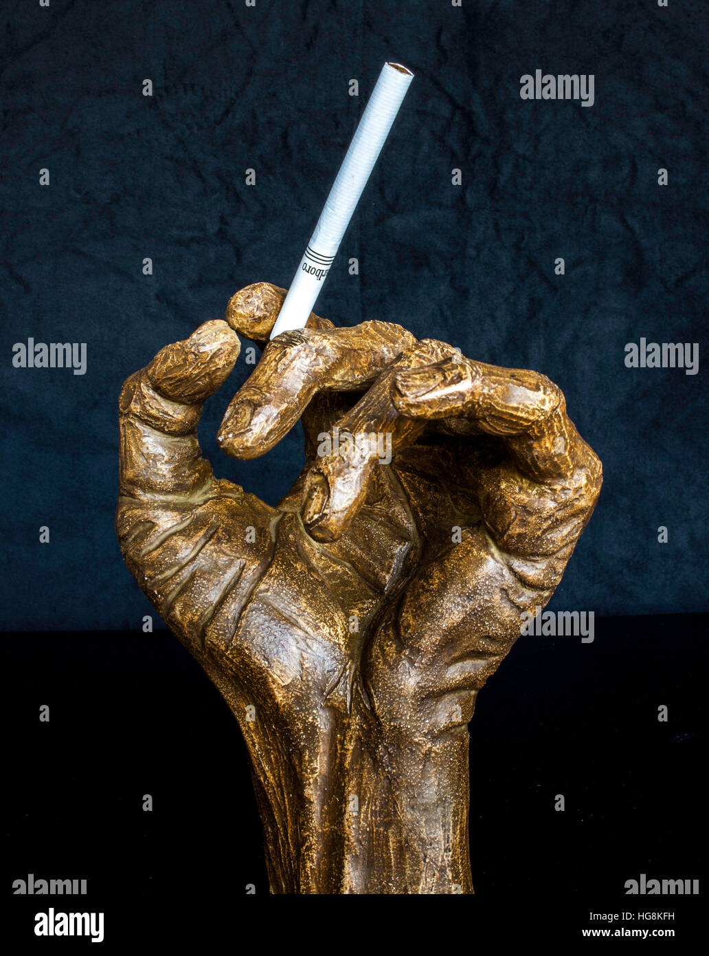 cigarette statue hand sculpture holding cigarette against black background Stock Photo cigarette statue hand sculpture holding cigarette against black background Stock Photo