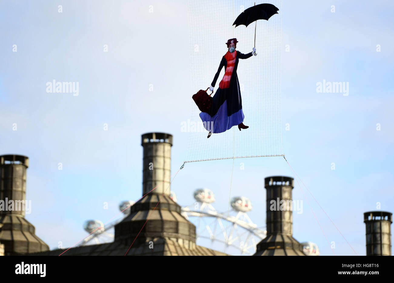 A drawing of Mary Poppins wearing a pollution mask is suspended in front of the roof of Portcullis House and the London Eye by Greenpeace campaigners after it was revealed that legal air pollution limits for the whole year have been broken just five days into 2017. Stock Photo