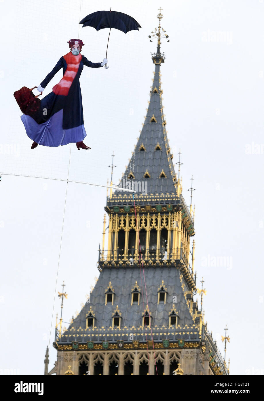 A drawing of Mary Poppins wearing a pollution mask is suspended in front of the Queen Elizabeth Tower at the Palace of Westminster by Greenpeace campaigners after it was revealed that legal air pollution limits for the whole year have been broken just five days into 2017. Stock Photo