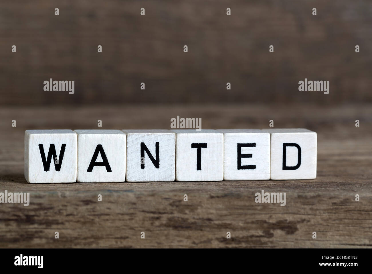 Wanted, written in cubes on wooden background Stock Photo