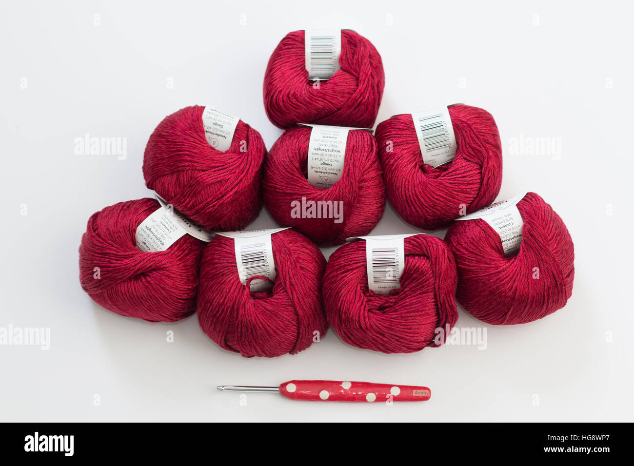 Eight red balls of wool with red novelty crochet hook on white background Stock Photo