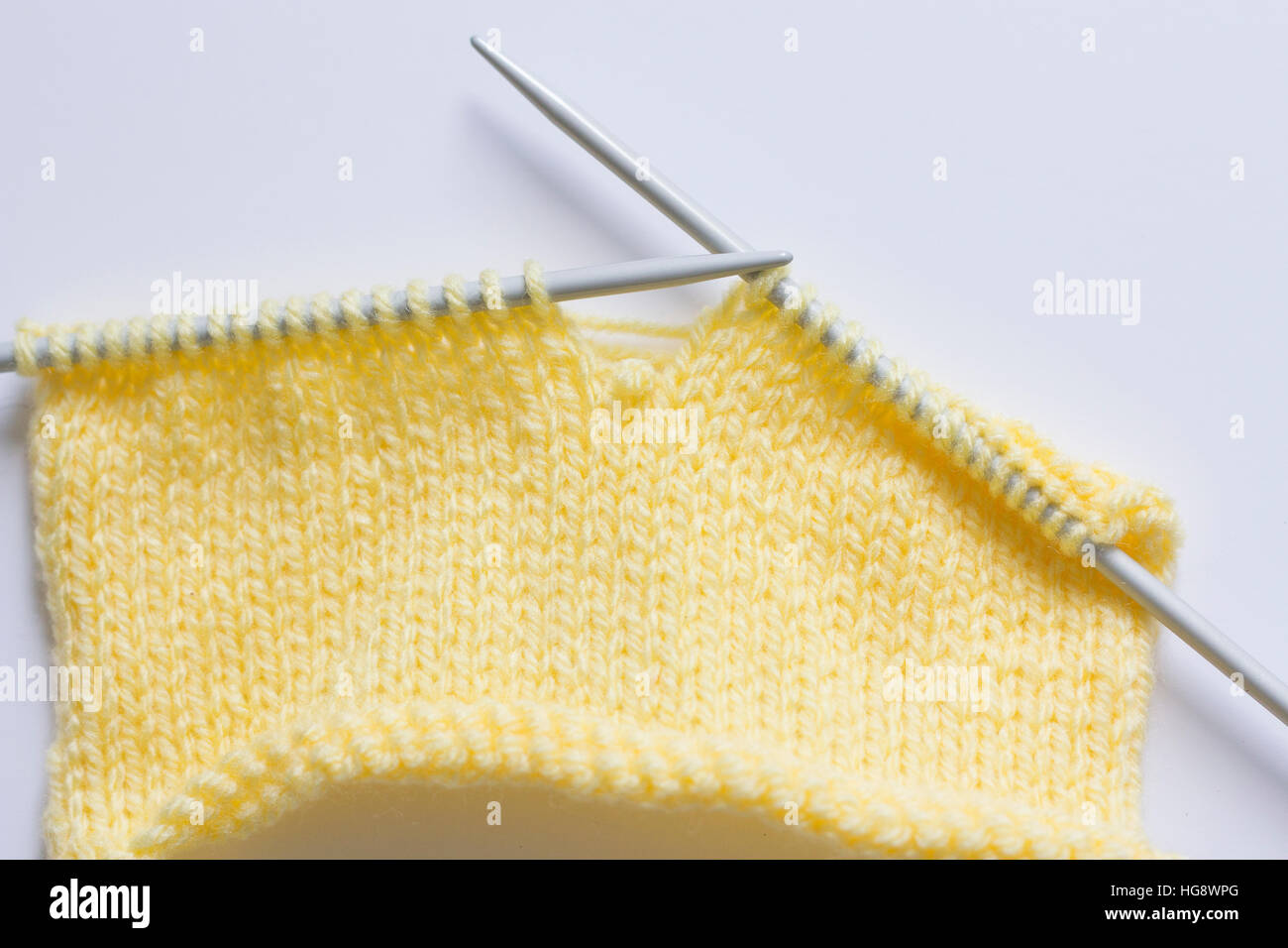 dropped stitch in piece of yellow knitting Stock Photo