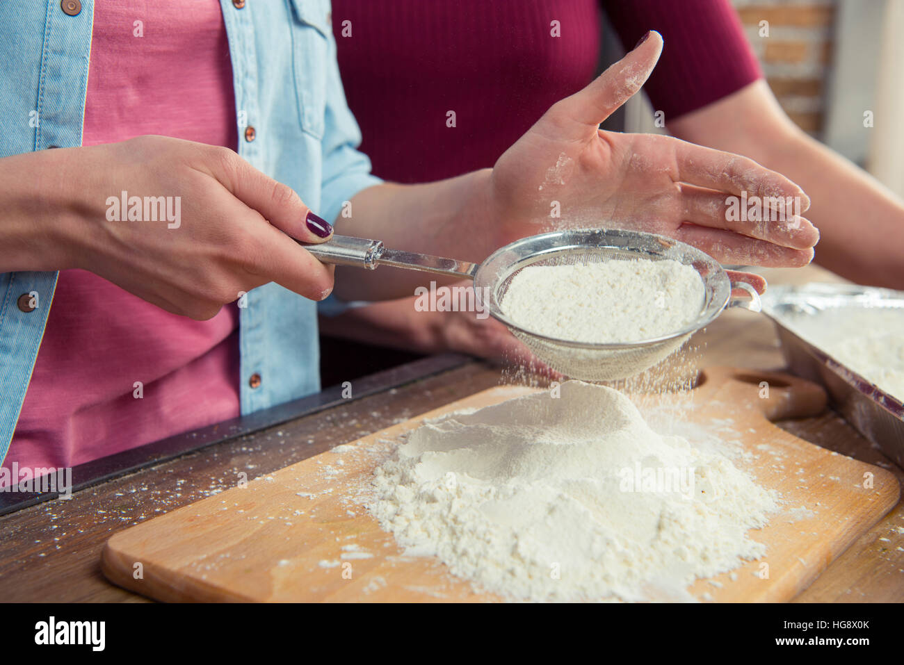 Partial view of woman sifting flour on cutting board Stock Photo