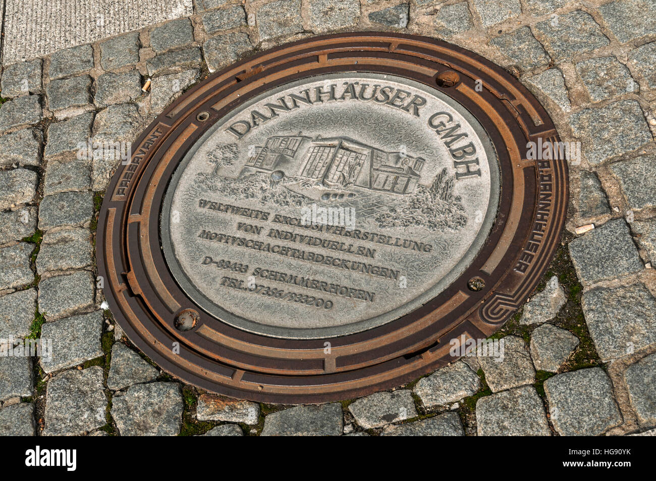 Man-hole cover with self promotion, Germany. Stock Photo