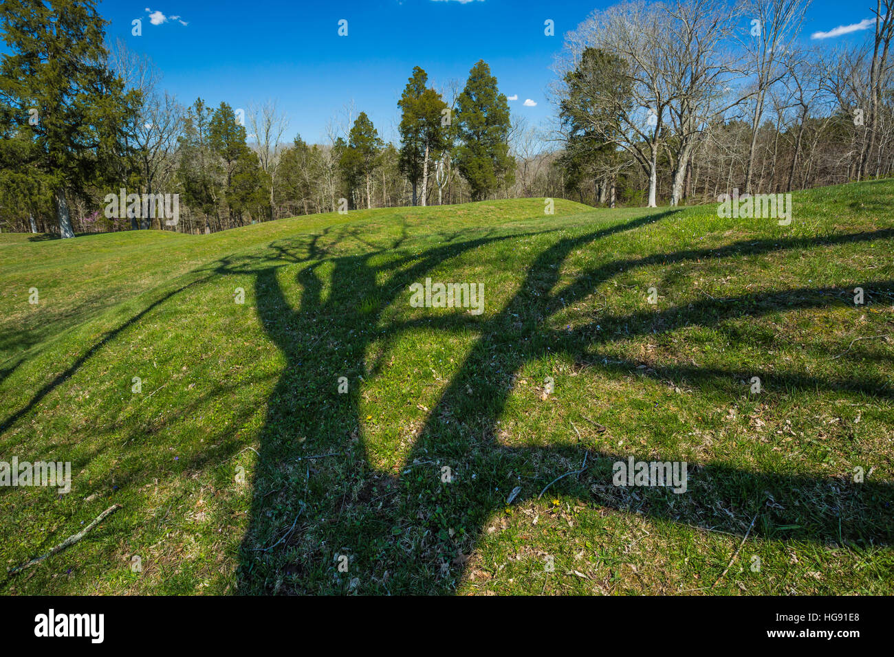 Spring tree shadows crossing part of the Great Serpent Mound, which snakes about ¼ mile over the landscape at Serpent Mound State Memorial in Adams Co Stock Photo