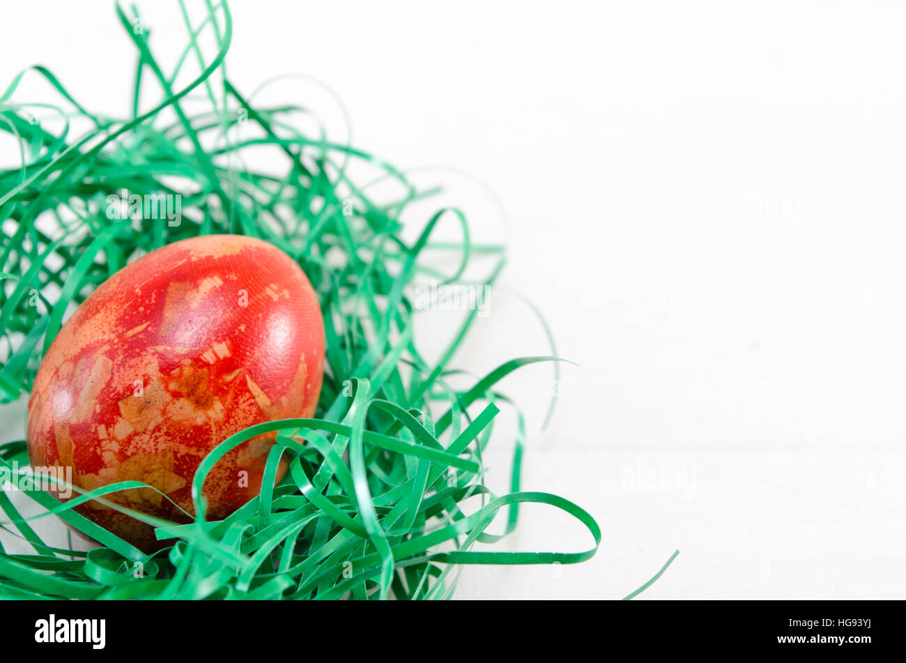 Painted Easter egg in green straw on a table Stock Photo