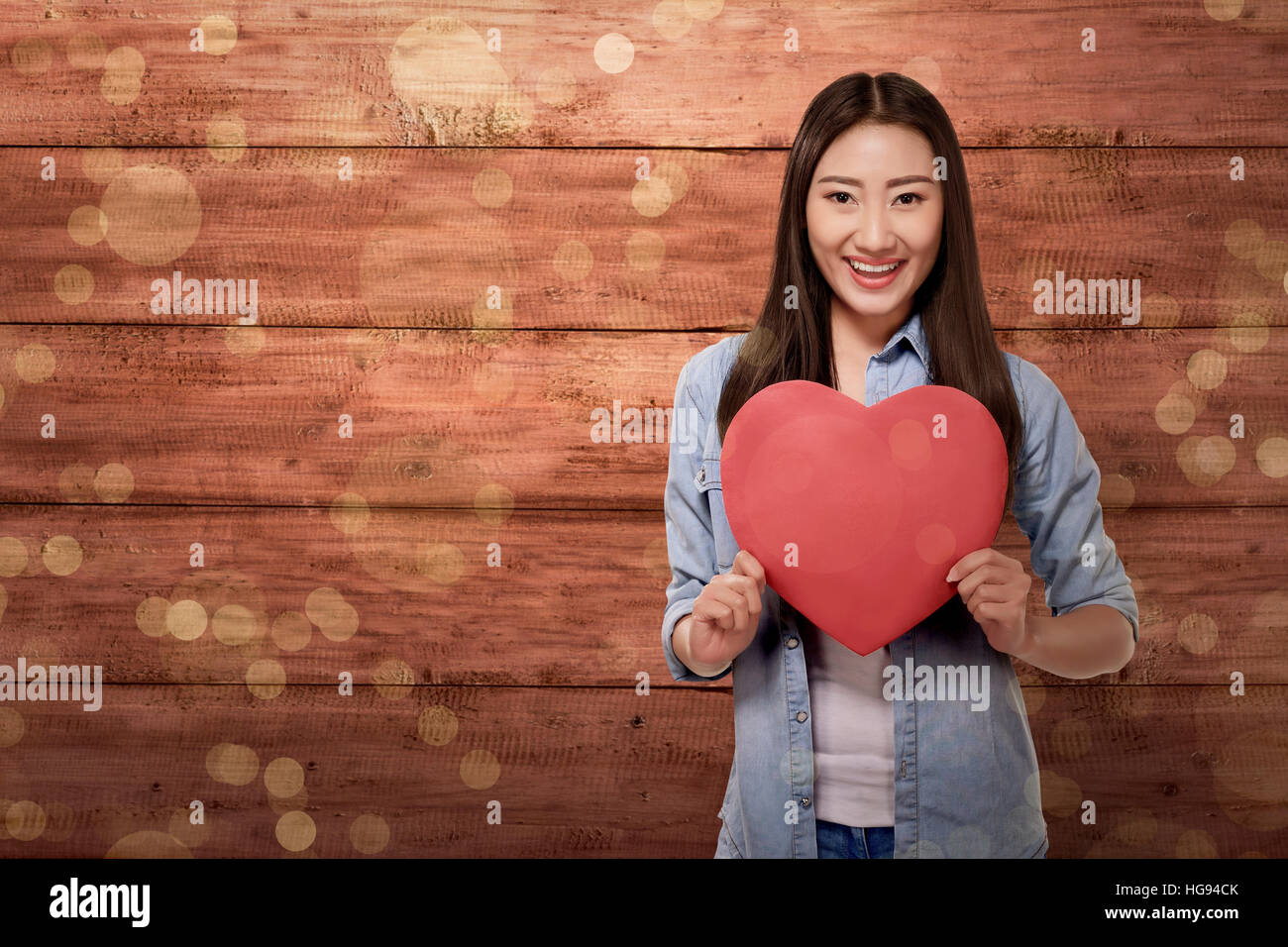 Beautiful asian woman holding red heart shape over wooden plank ...