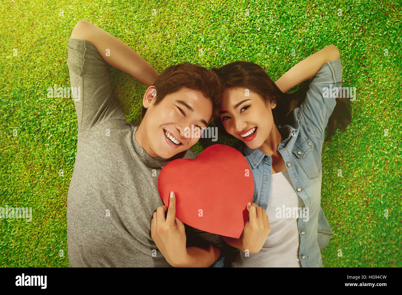 Romantic asian couple holding heart shape with lying on the grass Stock ...