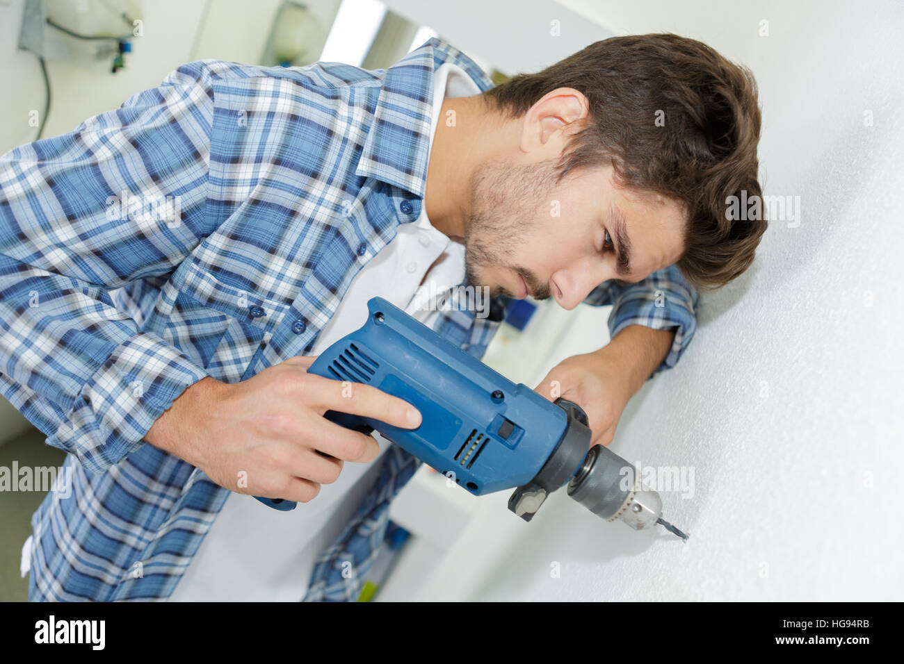 male builder drilling holes in wall at construction site Stock Photo