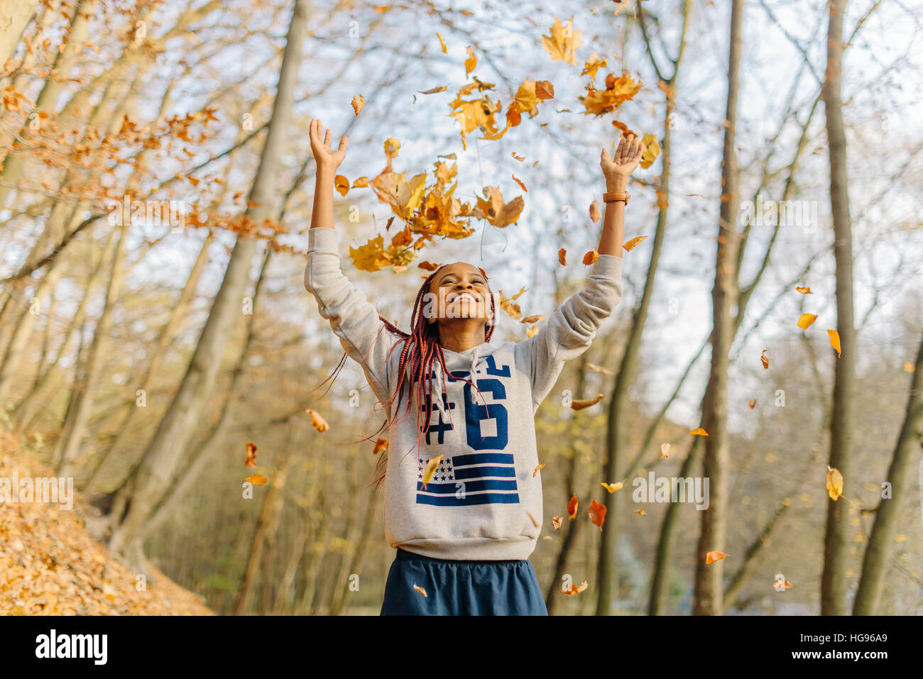 african girl playing with bunch of leaves, enjoying warm autumn day in park. Have fun in autumn Stock Photo