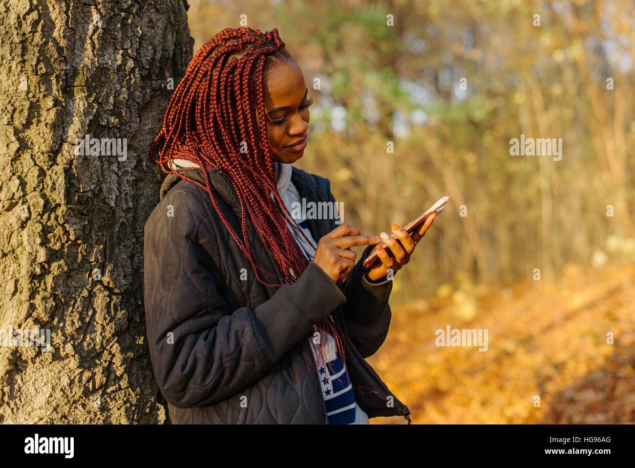 Pretty woman standing near tree in the autumn park at sunset. Girl ...