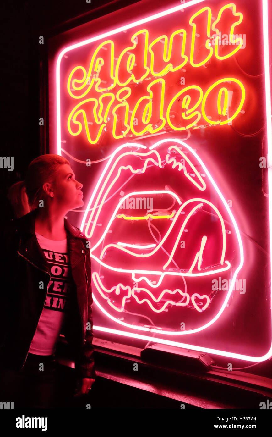 Blonde model poses in front of neon signs in London's famous Soho area. Stock Photo