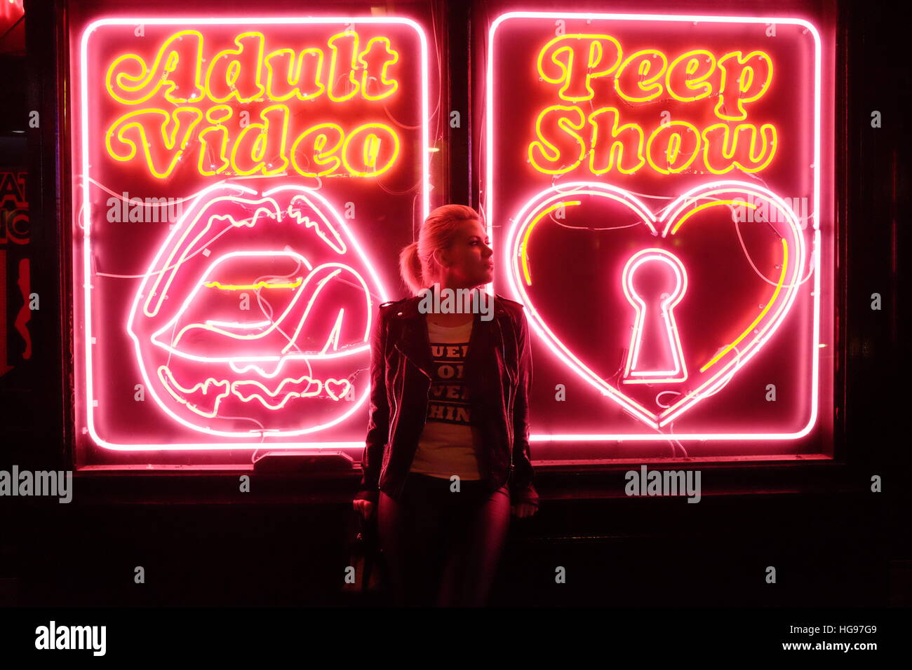 Blonde model poses in front of neon signs in London's famous Soho area. Stock Photo