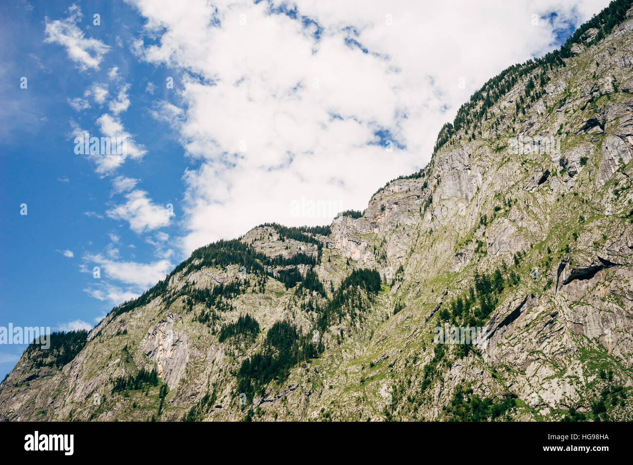 Massive mountain covered with trees and greenery against scenic cloudy sky Stock Photo