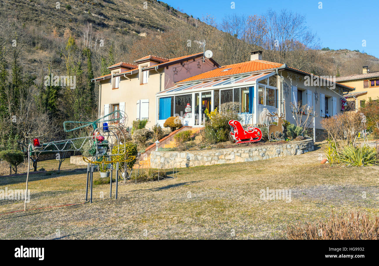 Sunny house with Christmas decorations in the garden including Santa in a helicopter, and sleigh with reindeer Stock Photo