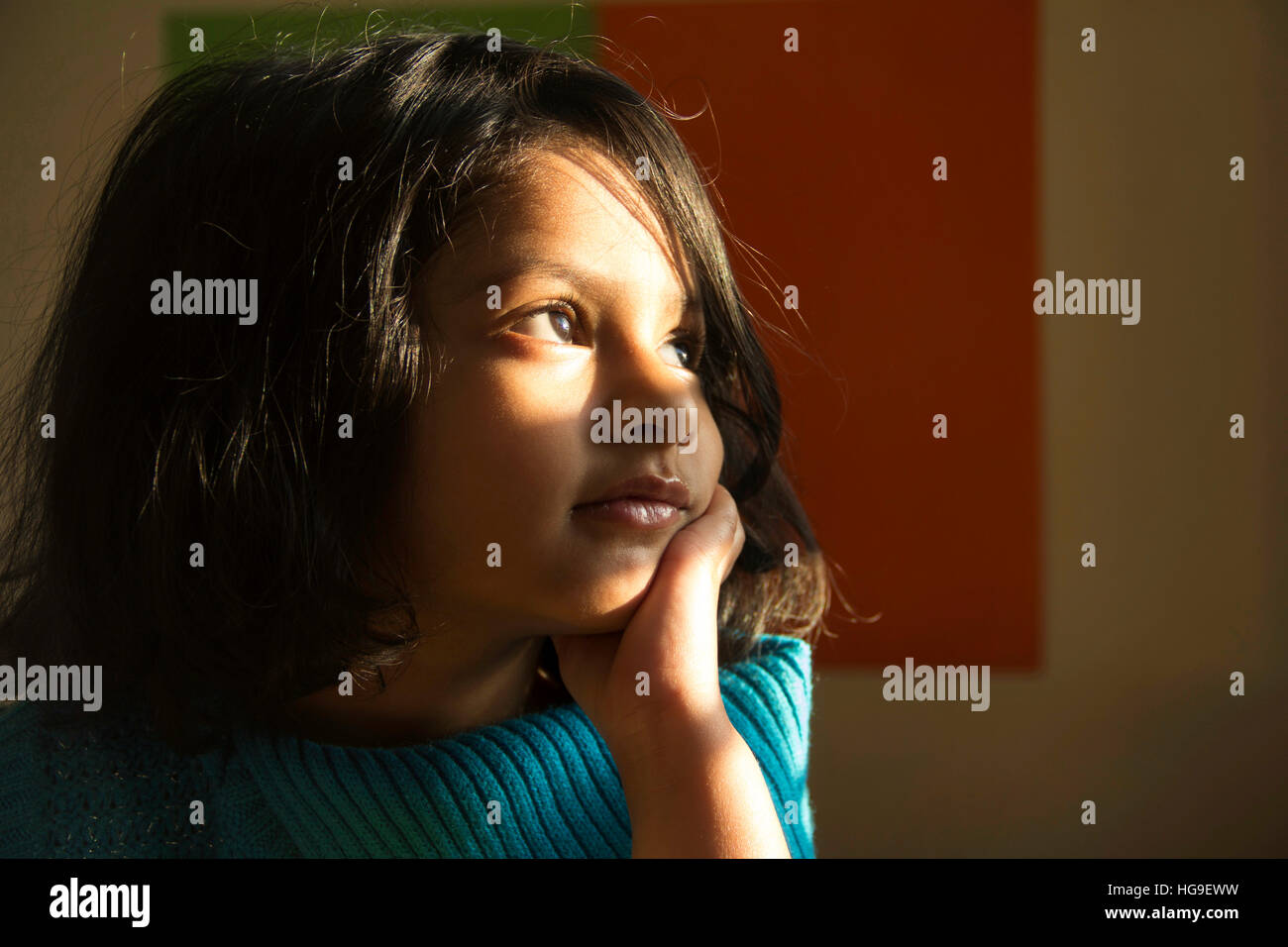 Close-up of cute little Indian girl dressed in blue looking towards the light Stock Photo