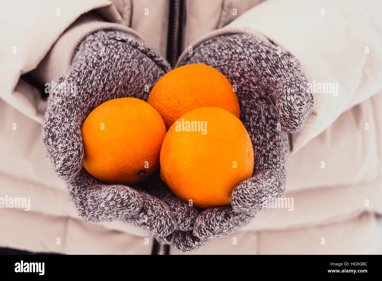 Hands in knitted gloves holding tangerines selective focus Stock Photo