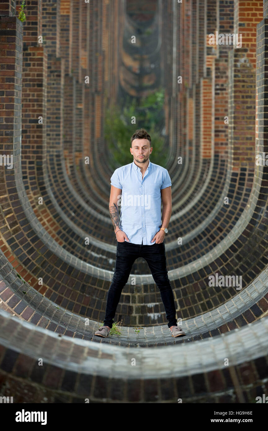 Singer, songwriter Jamie Mathias poses with his guitar for a shoot at the Ouse valley viaduct, Sussex, UK. Stock Photo