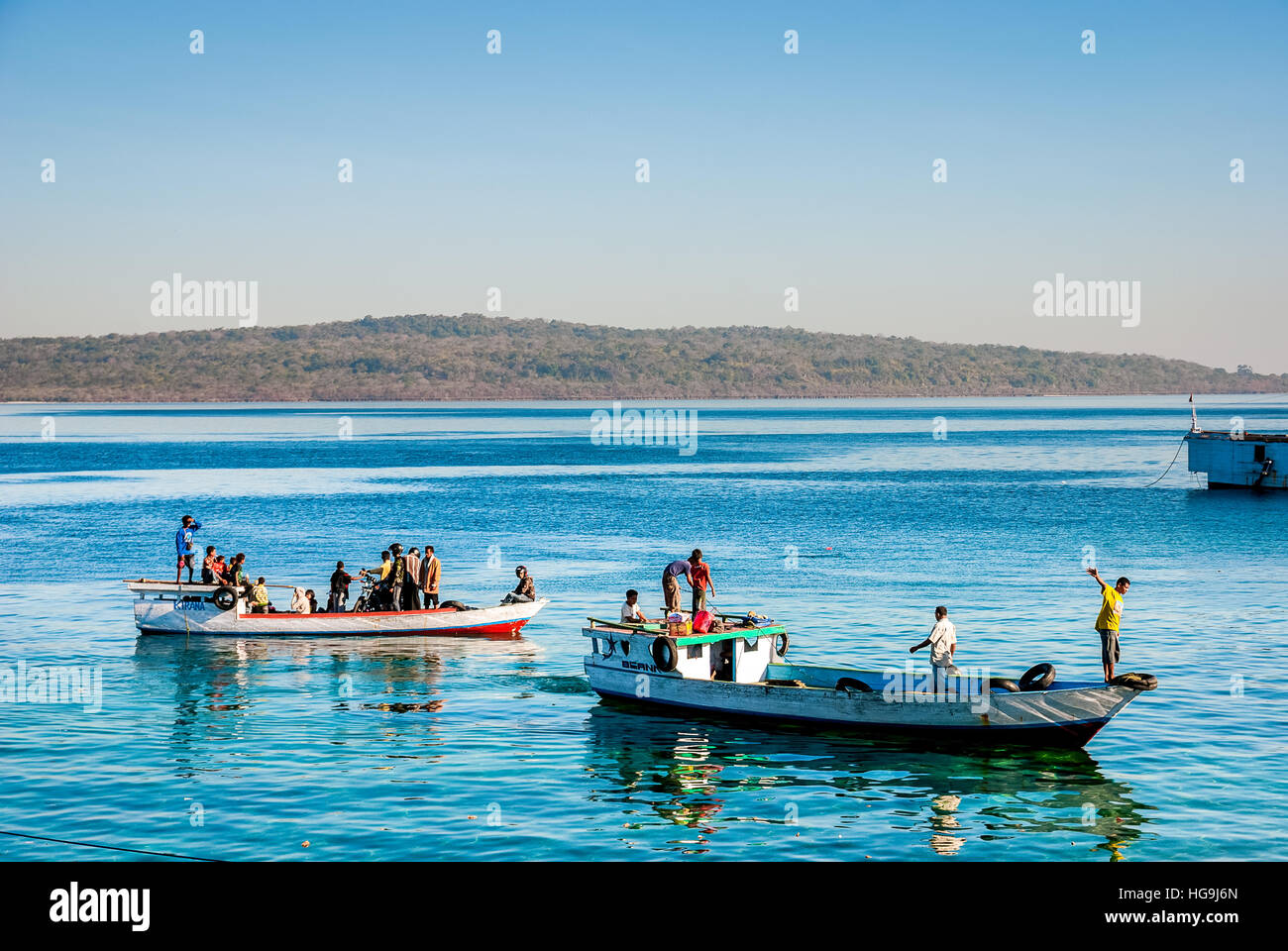 People standing on two wooden boats available for a rent as local transport, near Kupang ferry harbor in East Nusa Tenggara, Indonesia. Stock Photo
