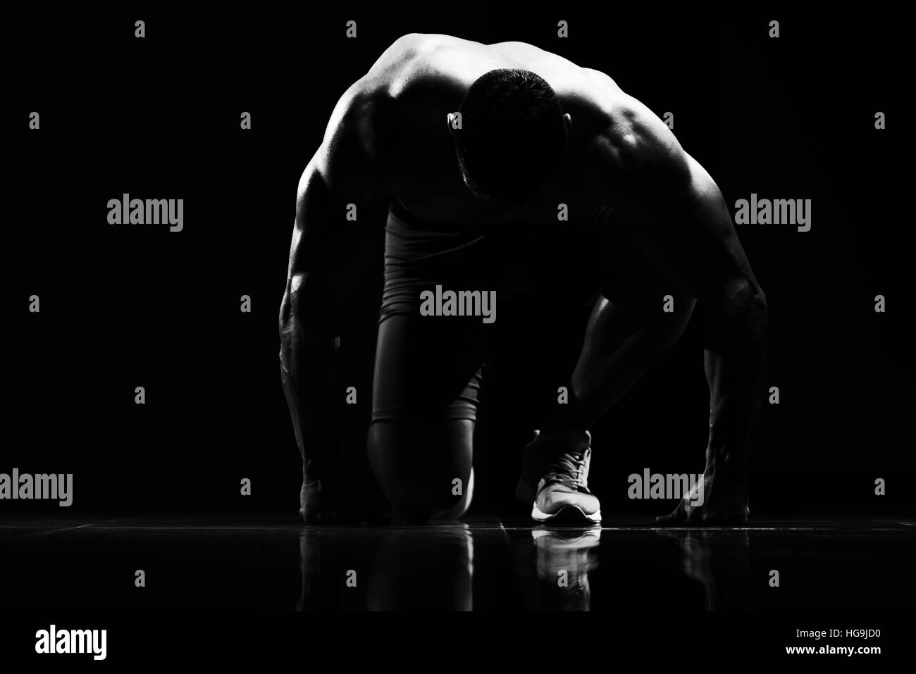 Strong Muscular Men Kneeling On The Floor - Almost Like Sprinter Starting Position Stock Photo