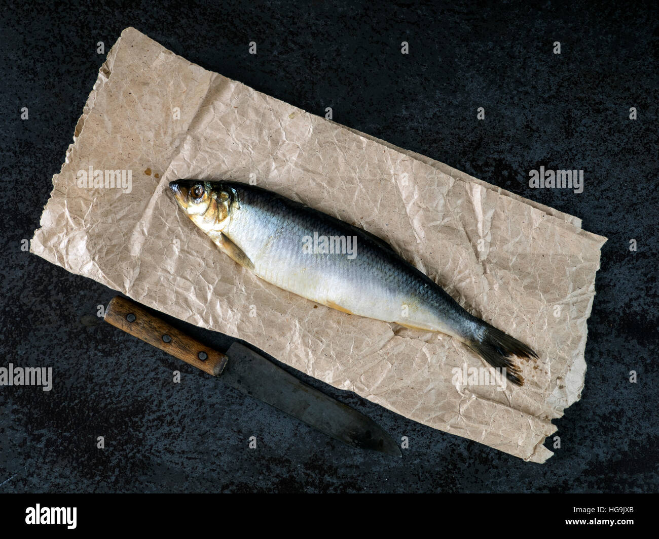 salted herring on a piece of crumpled wrapping paper Stock Photo