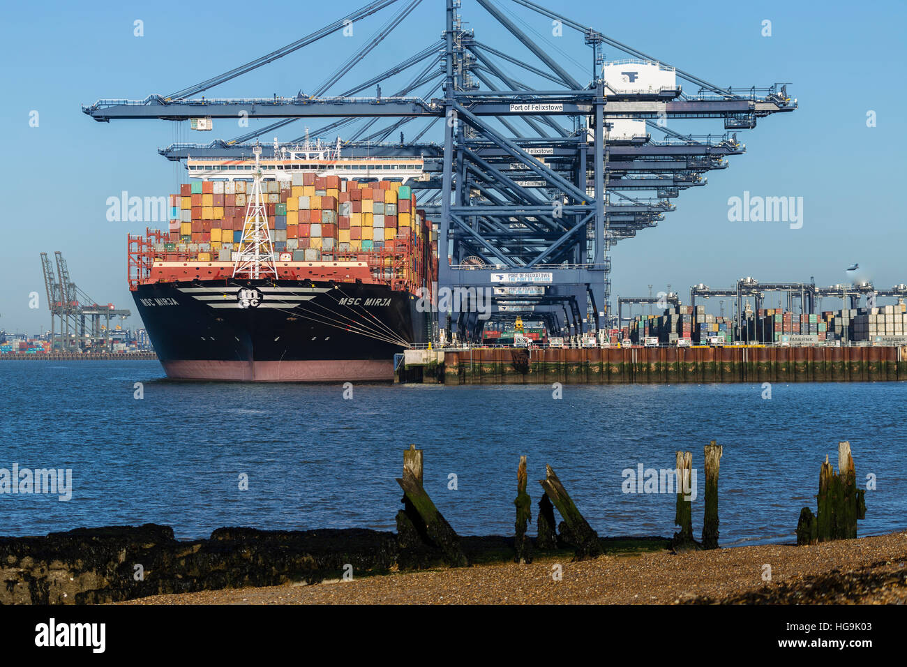 Container Ships in Port of Felixstowe with Shingle Beach and Old Wharf in Foreground Stock Photo
