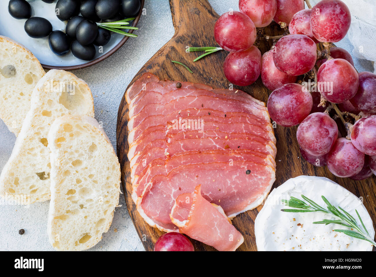 Cured meat, fresh baguette, grapes, cheese and black olives. Italian