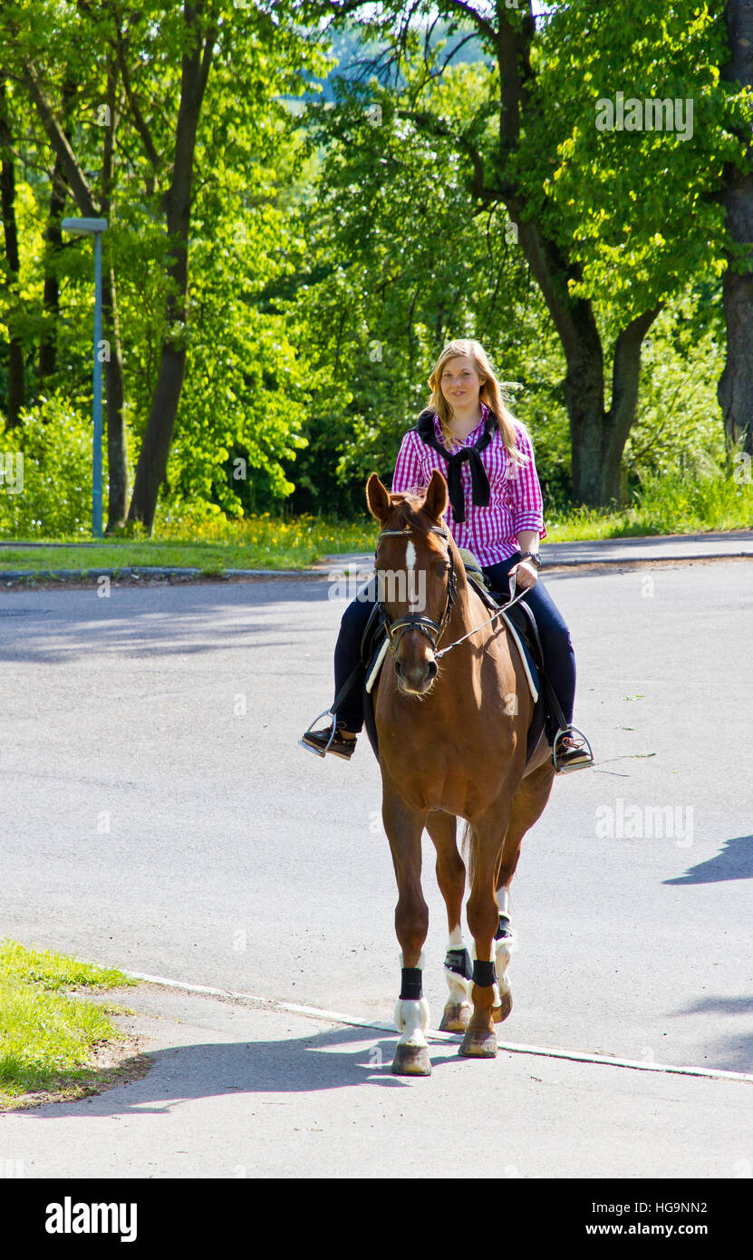 Young woman horseback riding on a street Stock Photo