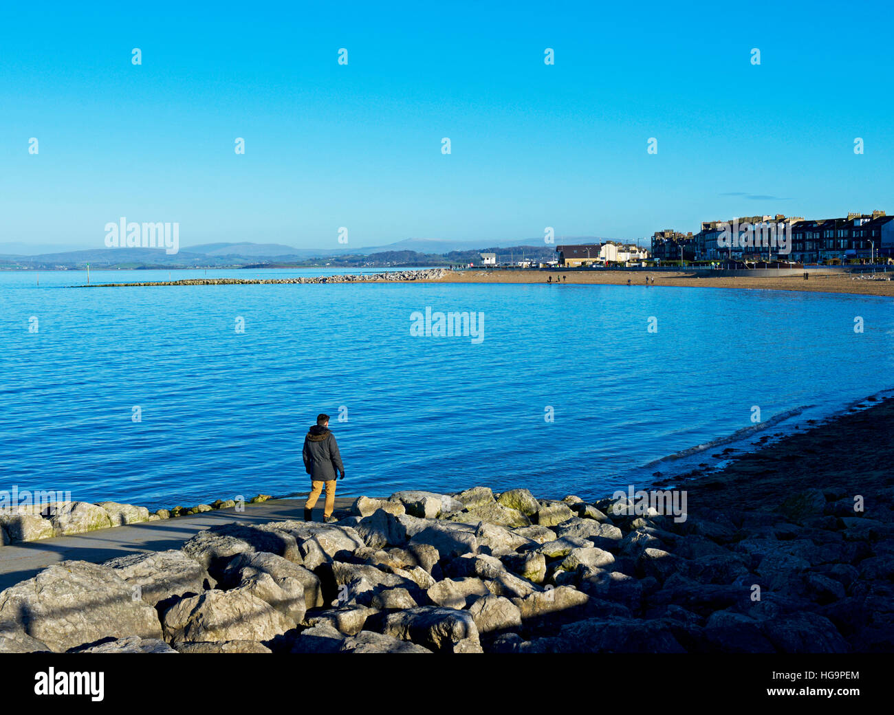 Man walking down to the beach at high tide, Morecambe, Lancashire, England UK Stock Photo