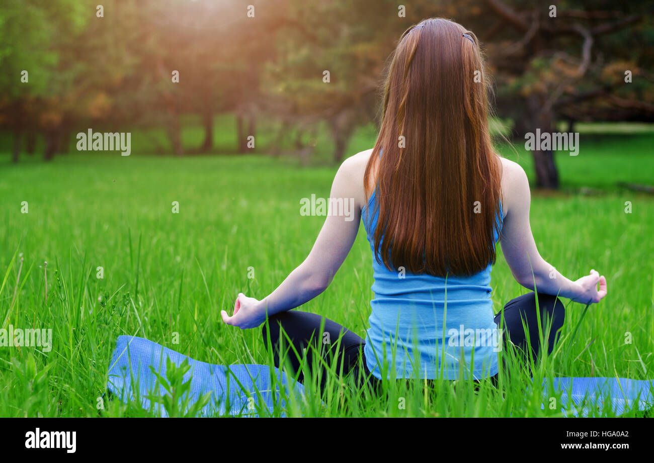 Young girl practicing yoga in nature in the woods on a background of green  trees and  covers a ray of sunshine at sunset Stock Photo - Alamy